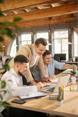 Obraz premium Teamwork with project. Young caucasian colleagues working together in a office using modern devices and gadgets. Look busy, attented, cheerful, successful. Concept of business, office, finance.