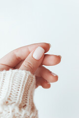 A woman's hand with a perfect natural neutral delicate manicure on a white background. A delicate color palette. Light nails in pastel colors