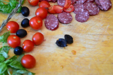 girl cuts vegetables, olives or tomatoes on a wooden board to make pizza Margherita pizza with utensils and vegetable on slate plate