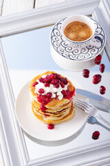 Pancake tower with cranberry marmalade, fresh cottage cheese and coffee for breakfast on  mirror