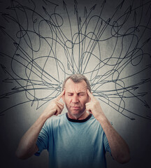 Middle aged man suffering headache and depression, keeps fingers to his temples, eyes closed....