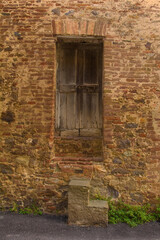 Fototapeta na wymiar An old wooden door in a disused residential building in the historic centre of the medieval town of Monticiano in Siena Province, Tuscany, Italy 