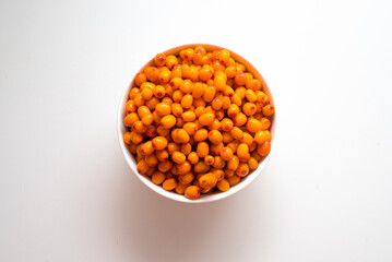 Bowl with sea buckthorn berries on a white background. View from above.