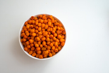 Bowl with sea buckthorn berries on a white background. View from above.