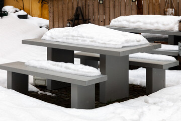 Stone street benches and tables outside, covered with white snow. Snowy winter concept, vacation