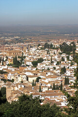 View of the city seen from the top of Alhambra Palace at Granada, Andalusia, Spain. The bird`s eye view of the city with lush greeneries looks beautiful on a sunny day