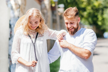 Happy and laughing man and woman holding hands walking along the road on a sunny day