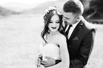 Sensitive portrait of a beautiful newlywed couple hugging in nature. Black and white photo.