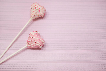 Pink and White Heart Shape Strawberry Covered Chocolate Pops On Pink Fabric Background