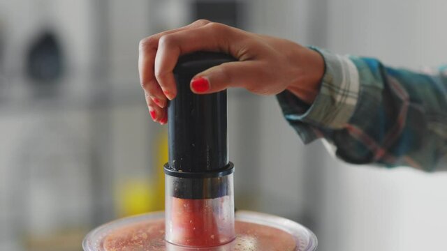 Close-up of young woman putting carrot and fresh fruti into blender mixing indredients making juicy smoothie for healthy skin. Nutrition, food and healthy lifestyle.