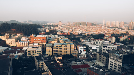 Obraz premium Morning in Guangzhou. There are small and tall houses and cars on the road below. Mountains in the background. China