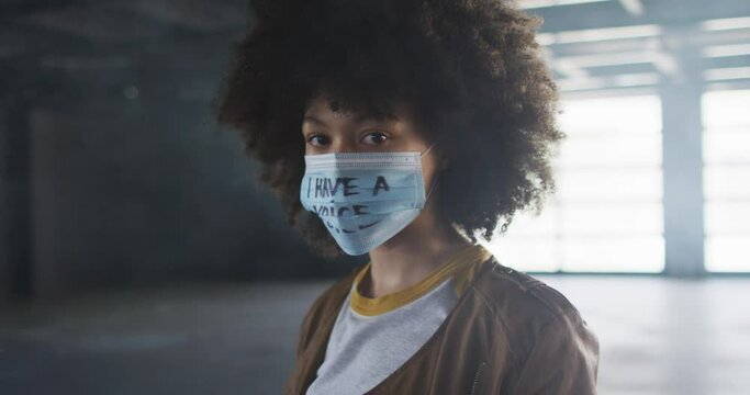 Portrait Of African American Woman Wearing Protest Face Mask In Empty Parking Garage