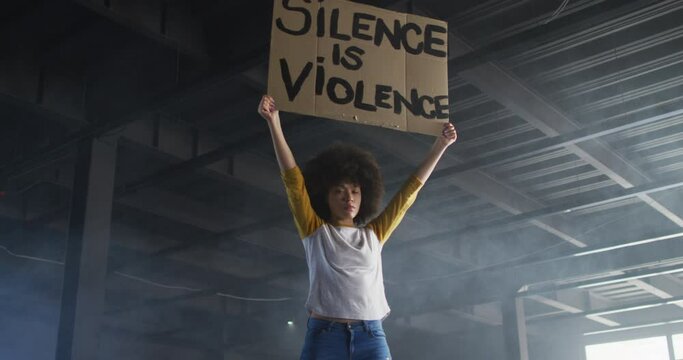 Portrait of african american woman holding protest placard in empty parking garage