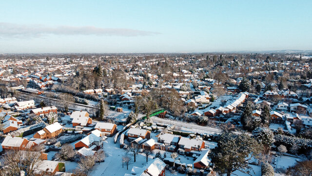 Snowy rooftops, railway track and bridge in snow covered British town, aerial drone