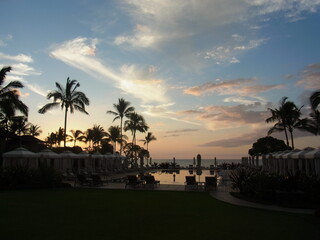 Beach, pool and palm trees in the beautiful sunset, sky  and clouds reflect in the pool