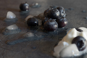Fototapeta na wymiar Spilled blueberries, yogurt, and ice on a dark blue back ground. Melting. 