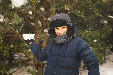 Teenage boy throws a snowball. Plays in winter in the park