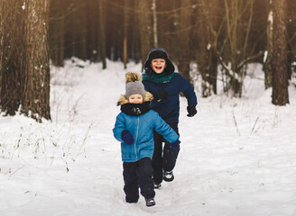 Fototapeta na wymiar Two boys run in the park in winter. Playing outdoors