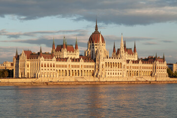 The Hungarian Parliament seen from across the Danube River, on the Buda side, is reflected in the river's waters as the evening lights turn orange, Budapest.