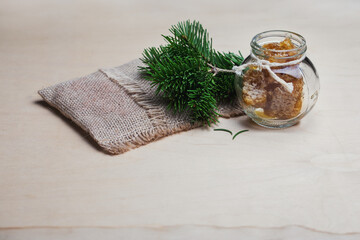 Natural composition: a jar of honey, a bouquet of pine branches and a burlap sponge.