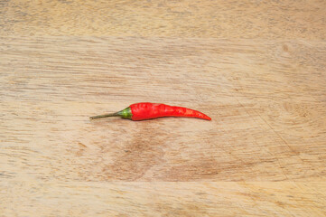 One red chili pepper on wooden background.
Top view.