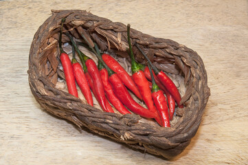 Red chili pepper on wicker basket on wooden background.
Top side view.