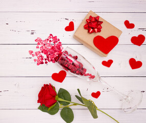 Red hearts flow out of champagne glass, gift box and rose
