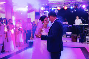 Young beautiful couple dancing in a restaurant celebrating a wedding. a woman in a white long dress, a man in a suit.