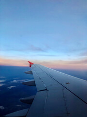 Obraz premium Sky and sunset from the plane window. Airplane wing. Open borders High quality photo Vertical mobile photo End of the pandemic. Travel to Europe and the world 