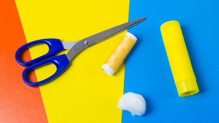 Scissors, glue, cotton wool and threads on multi-colored sheets of cardboard copy space. The process of making handmade garlands for Easter, banner format