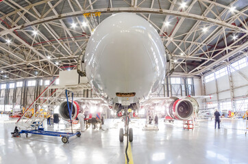 Aircraft in the under the hangar roof aviation industrial on maintenance, outside the gate bright light.