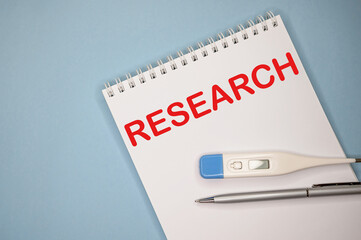 RESEARCH is written in a notebook on a blue background next to a pen and a thermometer.