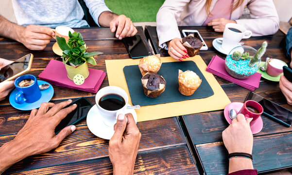 Top angle view of people with phones at coffee shop restaurant - Friends having breakfast with muffin cakes at cafe bar - Lifestyle concept on vivid filter with focus on lower left hand