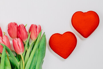 2 red hearts next to a bunch of tulips. Flowers as a gift. Valentine's day 