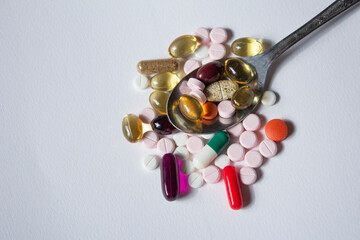 CUCHARADA DE PASTILLAS DE COLORES SOBRE FONDO BLANCO