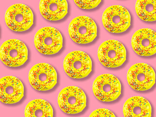 Pattern of yellow donuts with multi-colored sprinkles on a pink background.