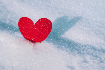 Lonely valentine. Red heart in cold, frosty morning snow. Valentine's Day greeting card. A symbol of love and romantic relationships. Congratulations on holiday of February 14. Copy space for text