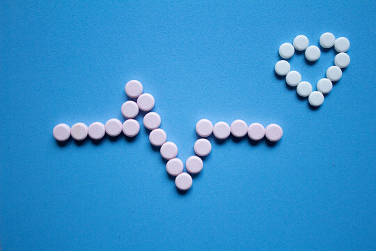 ELECTROCARDIOGRAMA Y CORAZ&Oacute;N DE PASTILLAS SOBRE FONDO AZUL