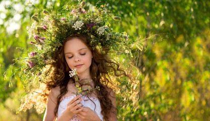 Cute smiling little girl  with flower wreath on the meadow at the farm. Portrait of adorable small kid outdoor.