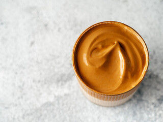 Trendy korean drink - dalgona coffee. Glass jar with cold or hot beverage - whipped instant coffee with milk on gray cement background with copy space. Top view or flat lay.