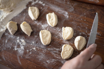 Senior woman hands rolling out dough in flour with rolling pin in her home kitchen