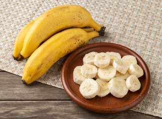 Bananas and slices on a plate over wooden table © Odu Mazza