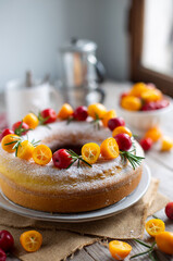 Ciambella agli agrumi decorata con kumquat,  piccole mele selvatiche e rametti di rosmarino su tavolo di legno