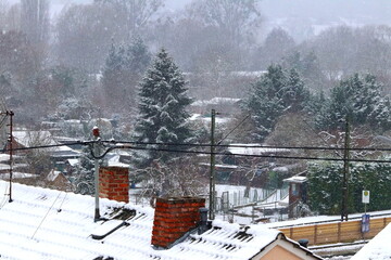 Frozen snowy winter landscape with roofs, brick chimneys and trees.