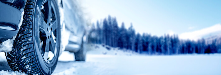 Winter tire. Detail of car tires in winter on the road covered with snow. Panorama, banner..