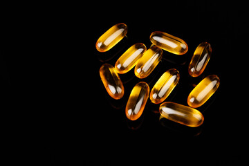 Omega-3 capsules on a black background. Health concept with fish oil capsules.