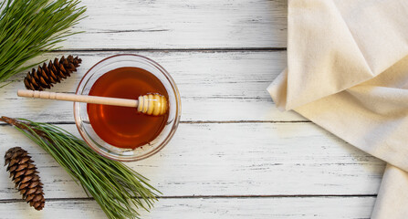 Pine honey in jar or bowl with honey stick and pine cones on wooden rustic table, healthy food 