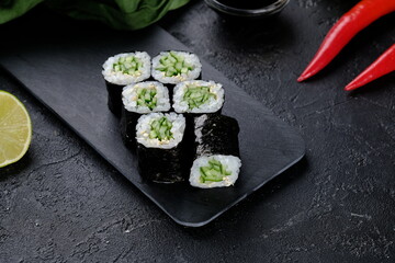 Vegetarian sushi roll with cucumber on black background