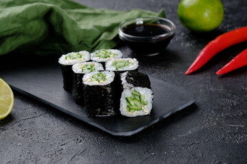 Vegetarian sushi roll with cucumber on black background