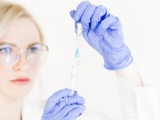 Hand holding syringe and vaccine.